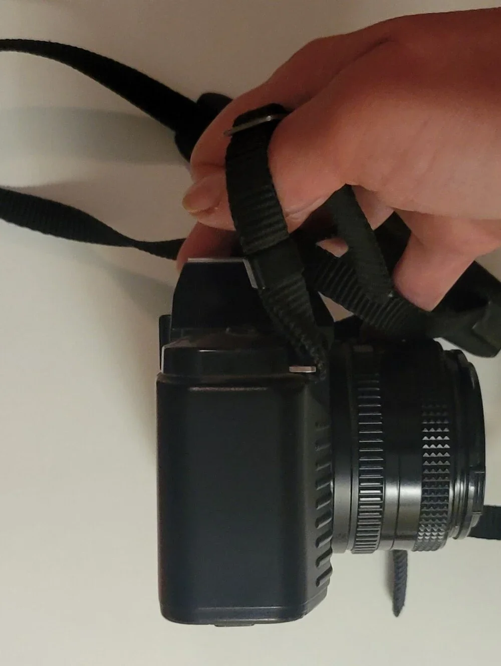 Canon black film camera with 50mm FD f/1.8 lens and neck strap